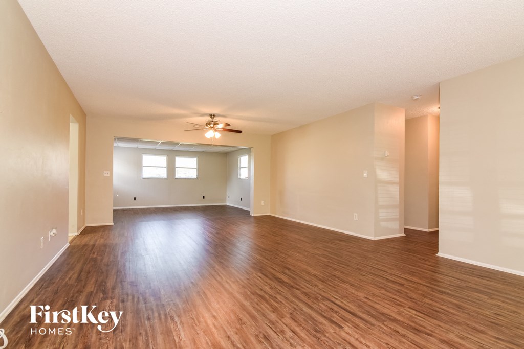 A spacious room with wooden floors and a ceiling fan.