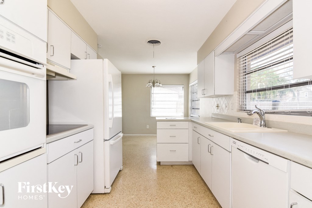 A kitchen with white appliances and cabinets.