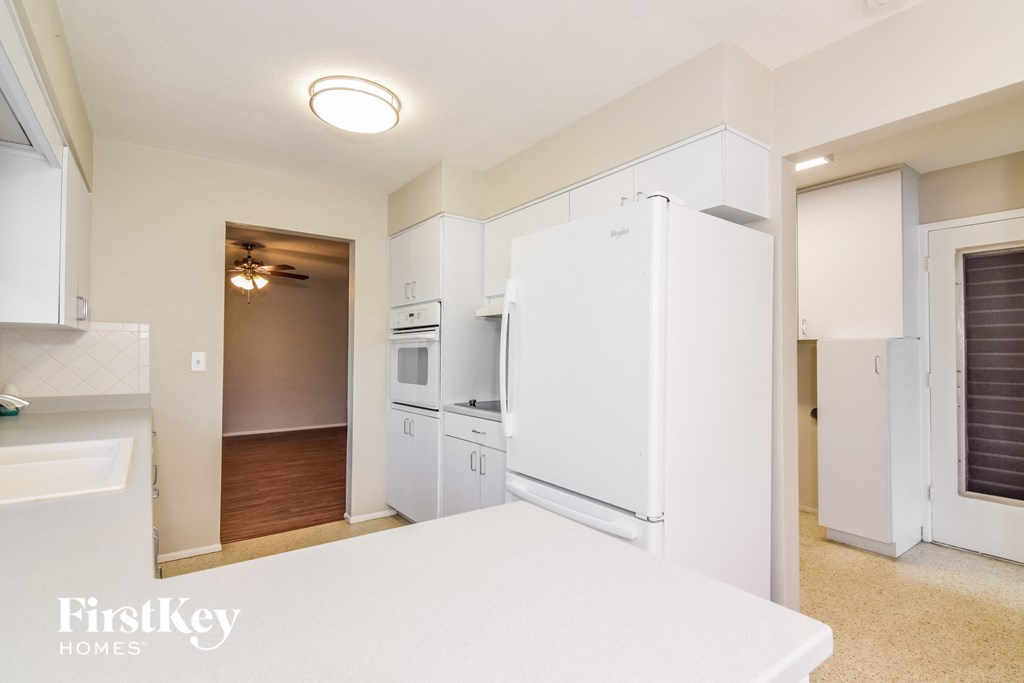 A kitchen with white appliances and a FirstKey Homes logo.