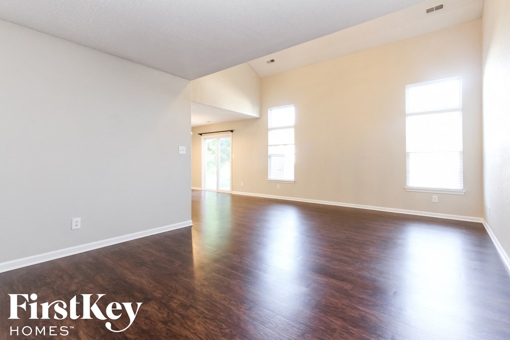 an empty living room with wood floors and white walls