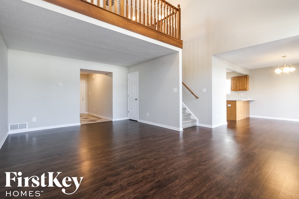 an empty living room with hardwood flooring and a staircase