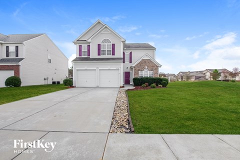 A house with a white garage door and a stone border.