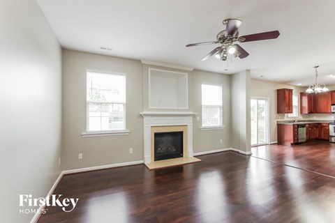 A spacious living room with a fireplace and a ceiling fan.