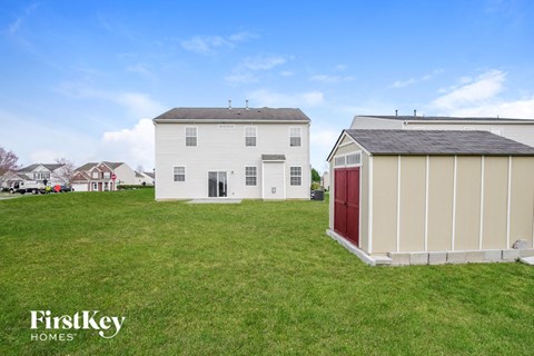 A white house with a red door is situated in a grassy field.