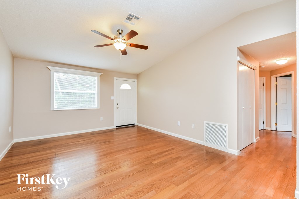 A room with a ceiling fan and wooden floors.