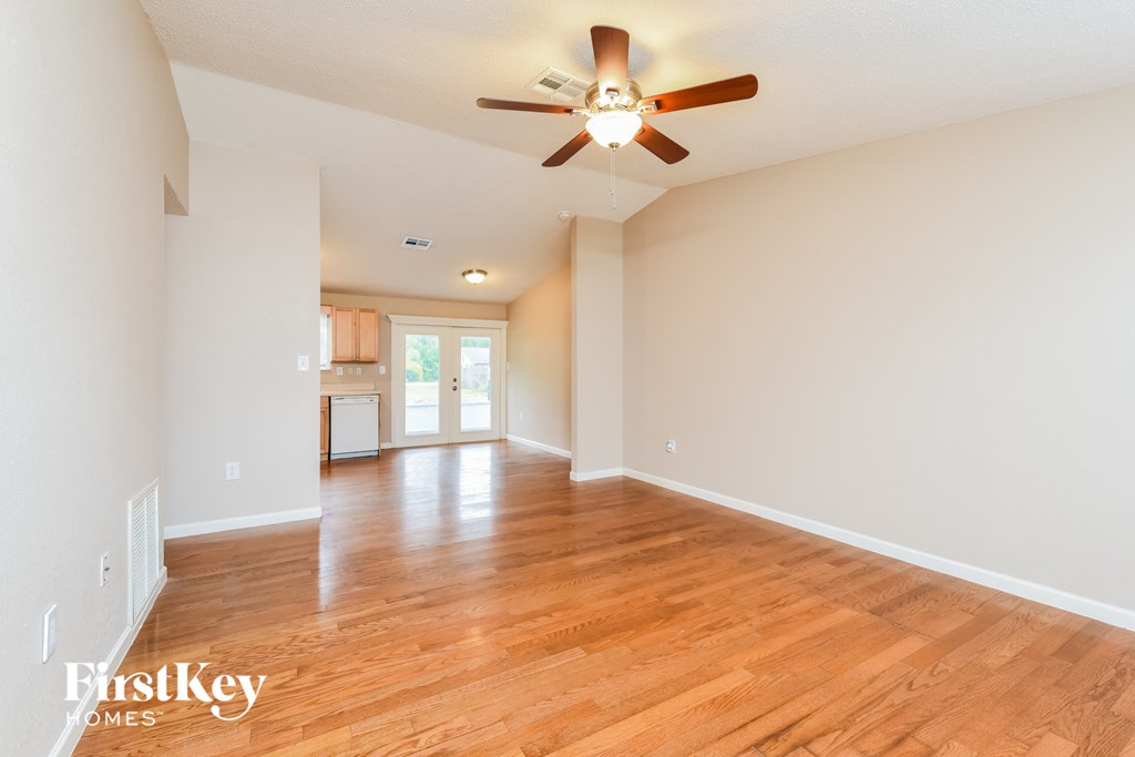 A spacious room with wooden floors and a ceiling fan.