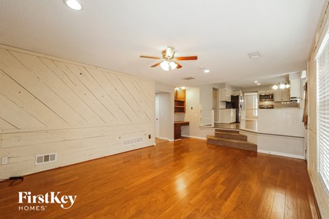 A spacious room with wooden floors and a ceiling fan.