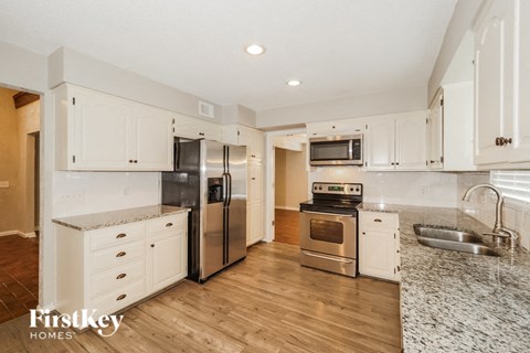 A kitchen with white cabinets and a stainless steel refrigerator.
