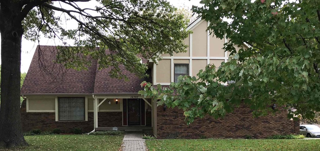 A house with a red roof and a tree in front.