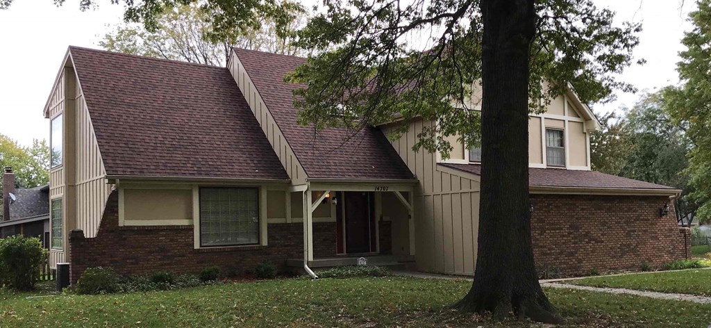 A house with a red roof and a tree in front.