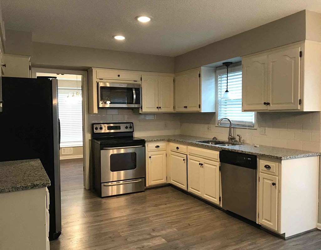 A kitchen with white cabinets and a black refrigerator.