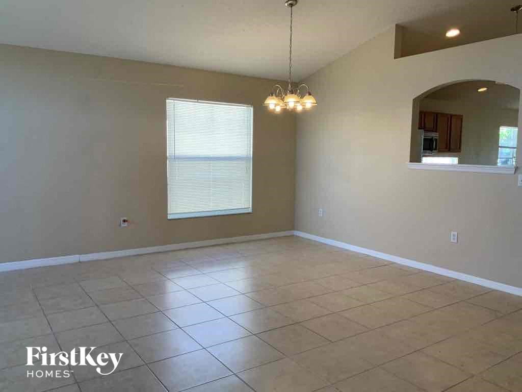 A spacious room with a large window and a chandelier hanging from the ceiling.