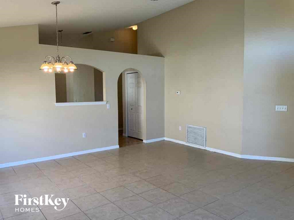 A room with a chandelier and a doorway leading to another room.
