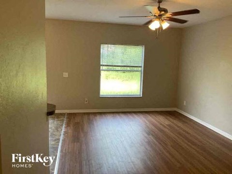 an empty living room with a ceiling fan and wood floors