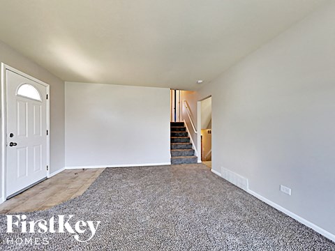 a living room with a carpeted staircase and a white door