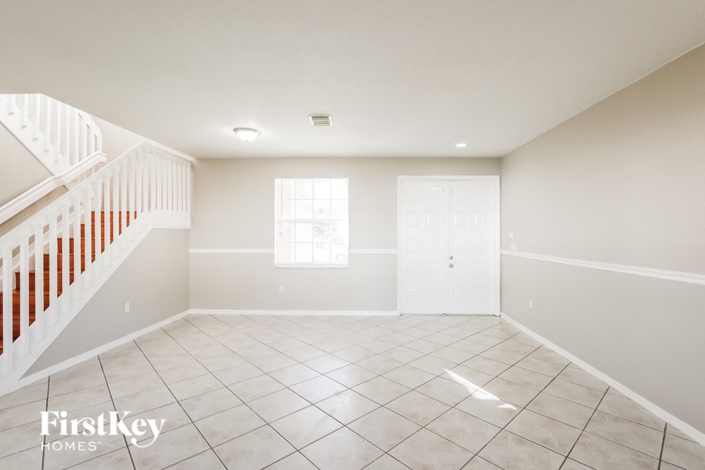 A spacious empty room with a tiled floor and a window.