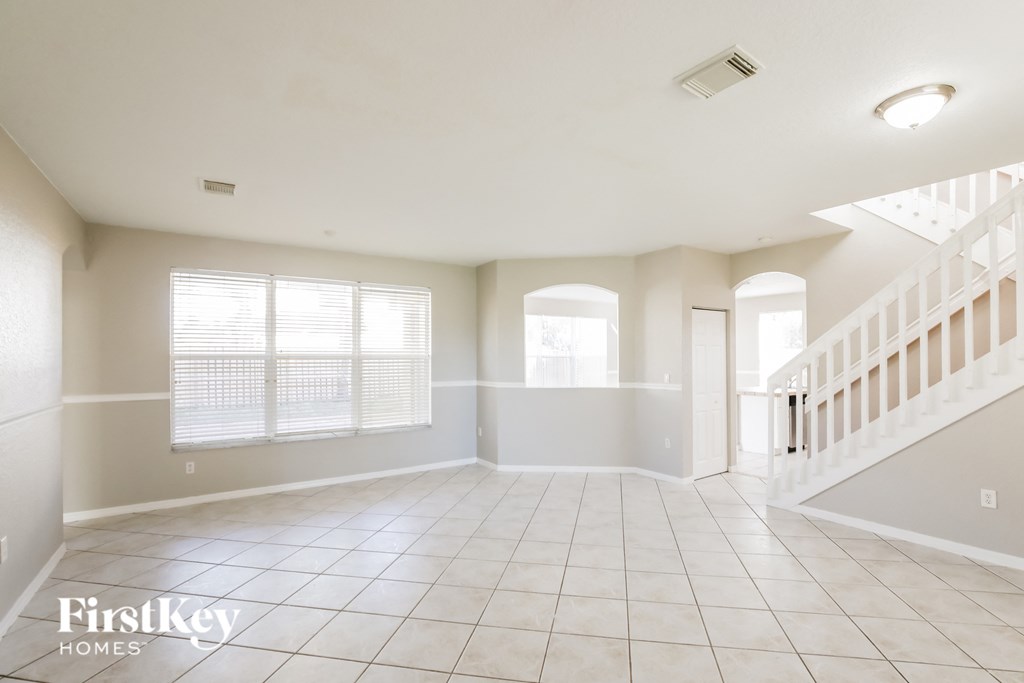 A spacious empty room with a staircase on the right side.