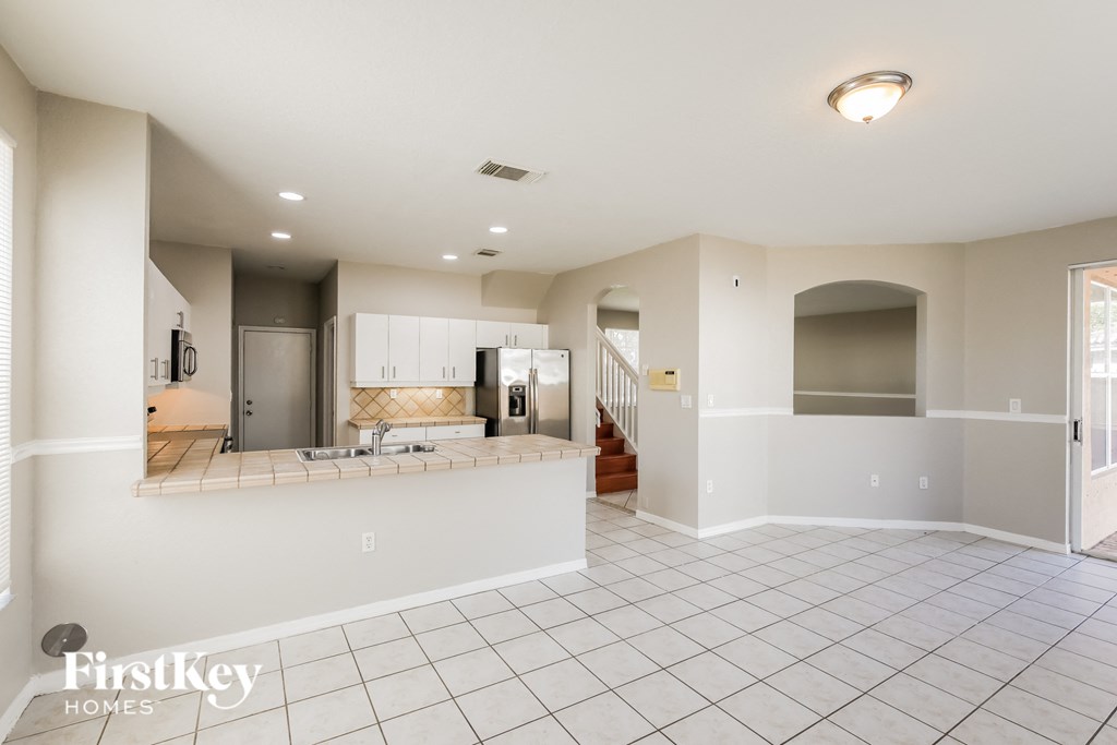 A spacious, empty room with a kitchen area in the background.