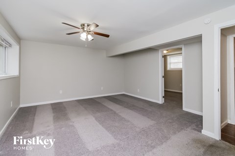 a living room with carpet and a ceiling fan