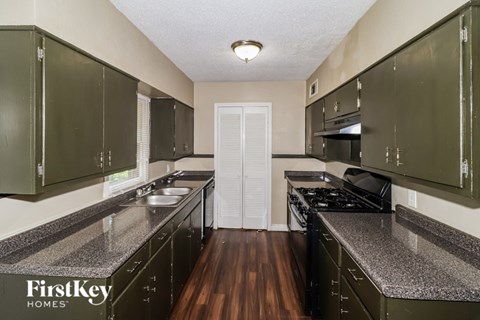 A kitchen with dark green cabinets and a white door in the middle.
