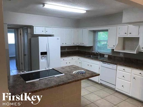 A kitchen with white cabinets and a brown countertop.