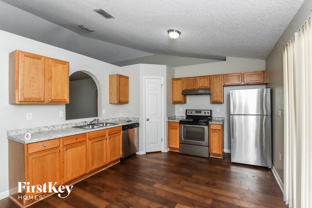A kitchen with wooden cabinets and a stainless steel refrigerator.