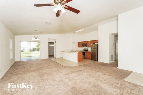 A spacious living room with a kitchen in the background.