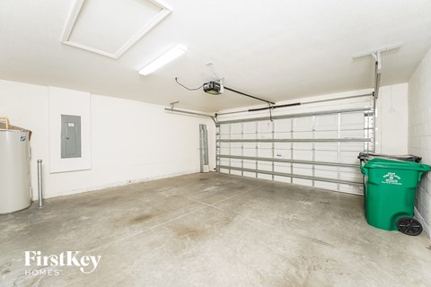A spacious garage with a green trash bin and a white door.
