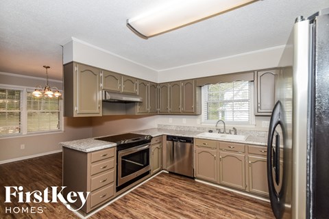 A kitchen with wooden floors and a black refrigerator.