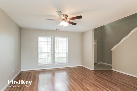 A room with a ceiling fan and wooden floors.