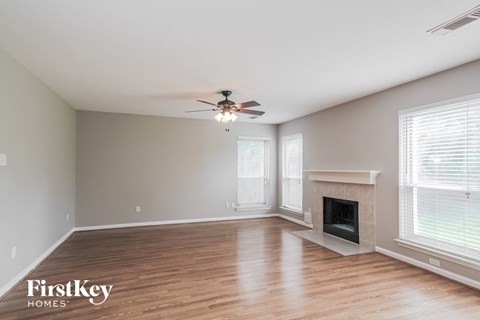 A spacious room with a fireplace and a ceiling fan.