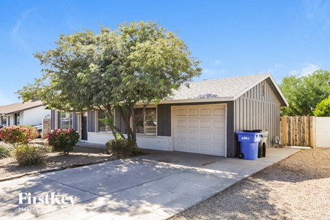 a small house with a garage and a tree in front of it