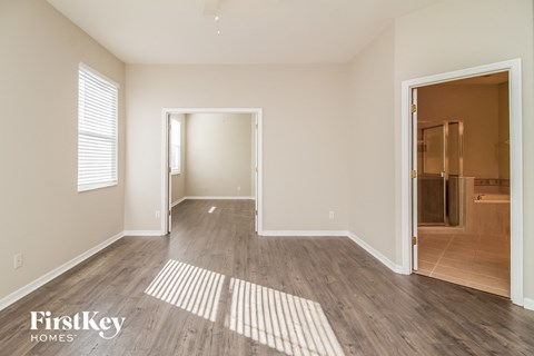 a spacious living room with wood flooring and a door to a bathroom