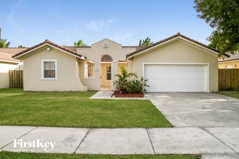 a beige house with a white garage door and a lawn