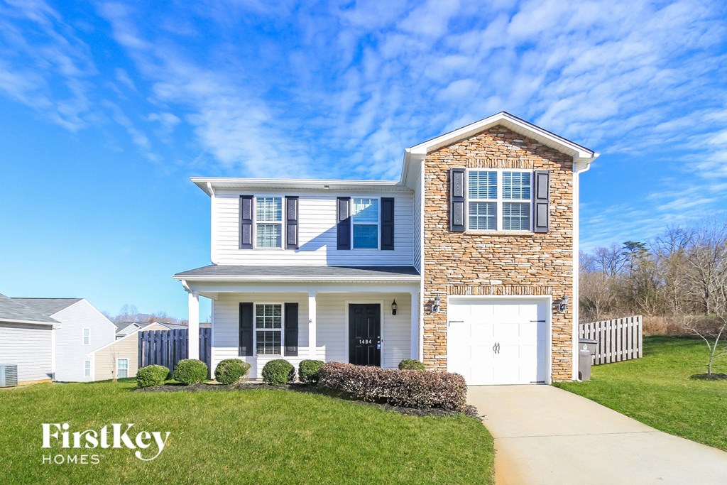 a white and brick house with a white garage door and a lawn