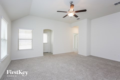 a spacious living room with white walls and a ceiling fan