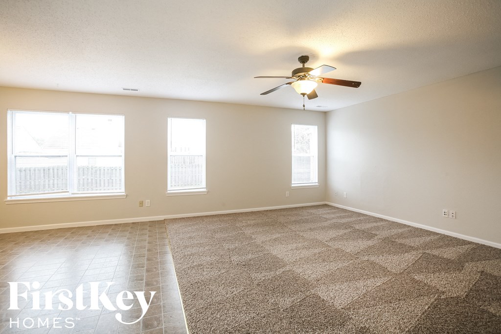 a living room with carpet and a ceiling fan