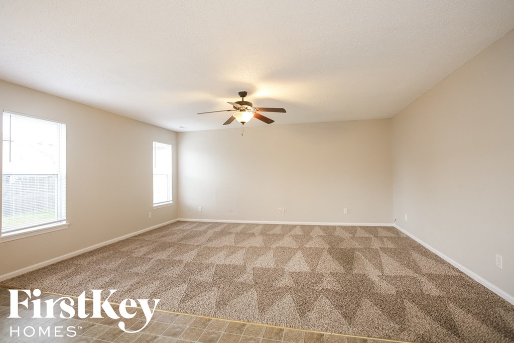 a living room with carpet and a ceiling fan
