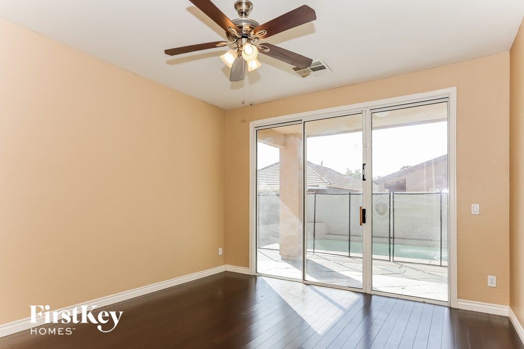 A room with a ceiling fan and sliding glass doors.