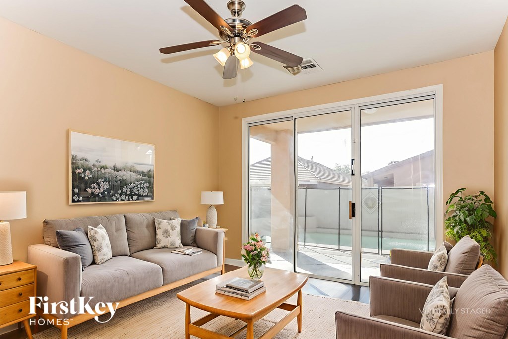 A living room with a grey couch, a wooden coffee table, a ceiling fan, and a painting on the wall.