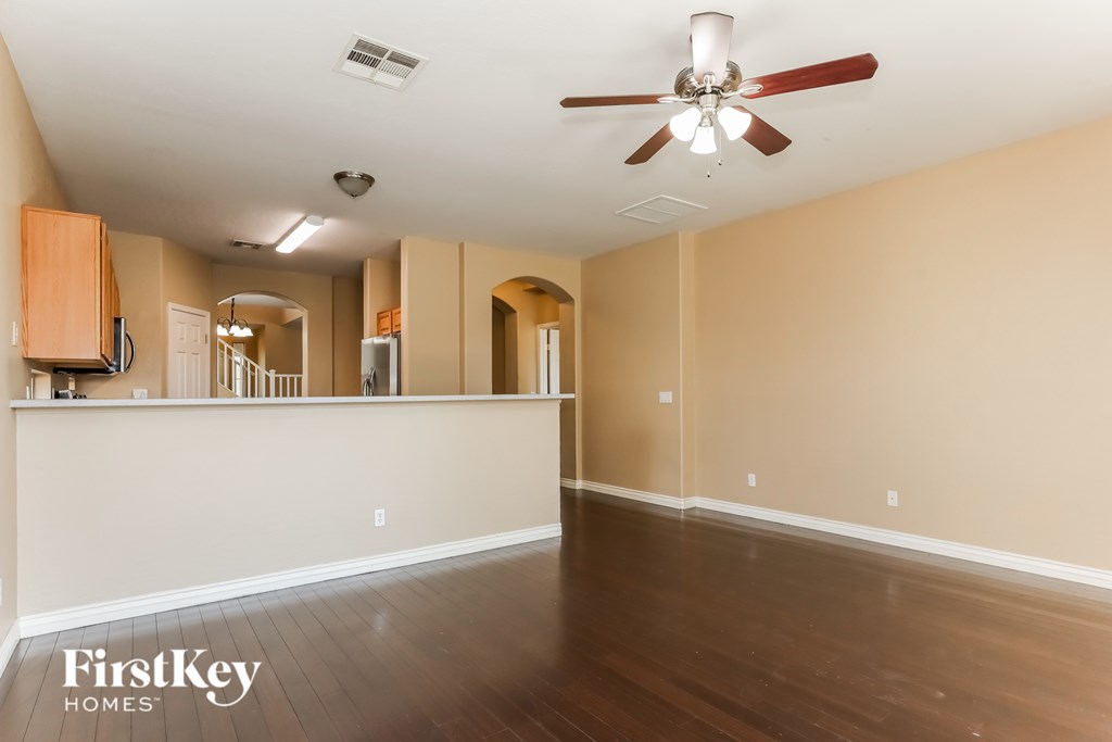 A spacious room with wooden floors and a ceiling fan.