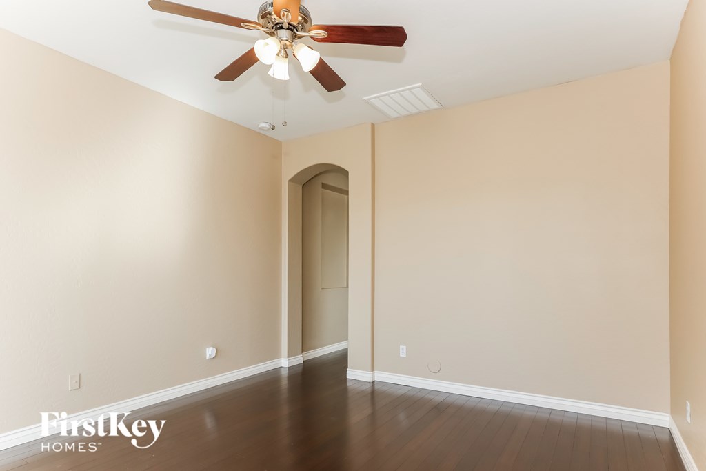 A spacious room with a ceiling fan and wooden flooring.