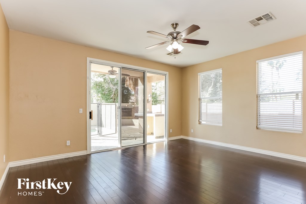 A spacious room with a ceiling fan and sliding glass doors leading to a balcony.