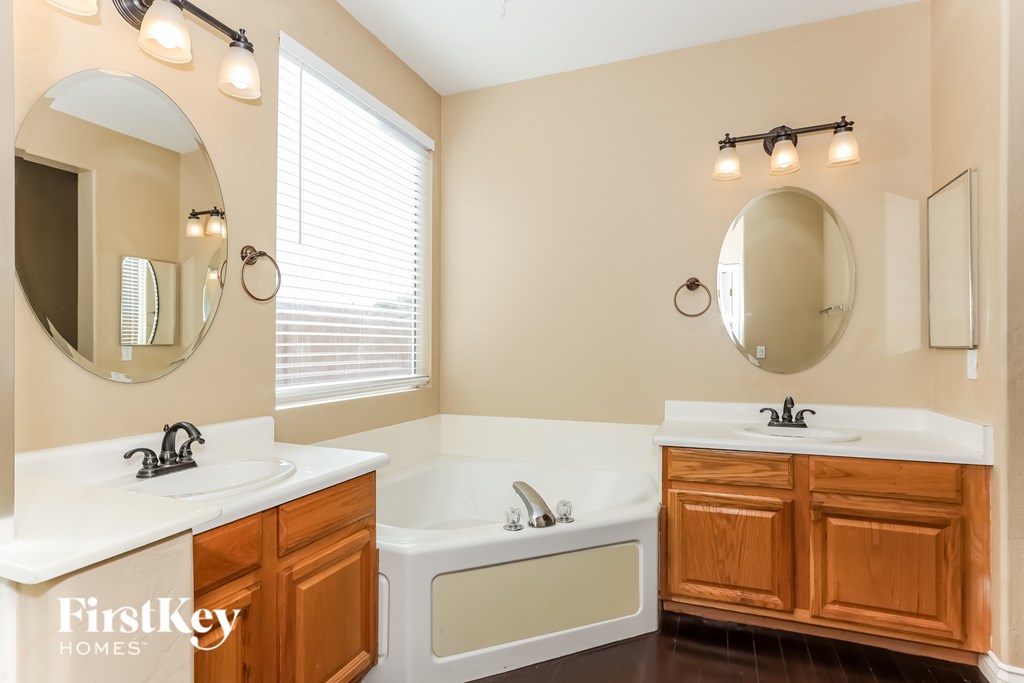 A bathroom with a tub, sink, and mirror.