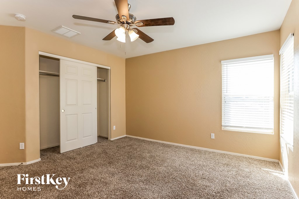 A room with a ceiling fan and a window with blinds.