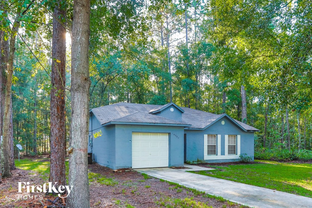 A house with a garage is surrounded by trees.