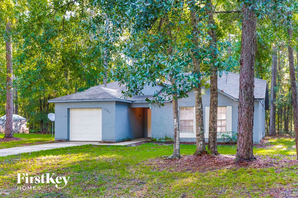 A house with a garage is surrounded by trees.
