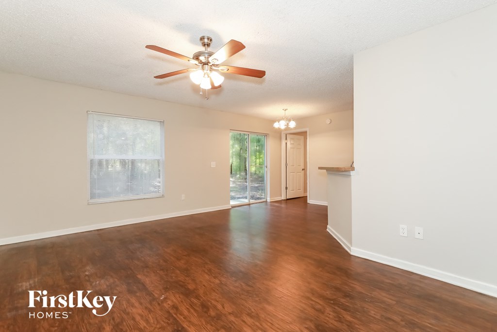 A room with a ceiling fan and wooden flooring.
