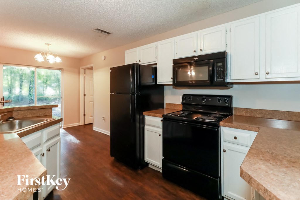 A kitchen with black appliances and white cabinets.