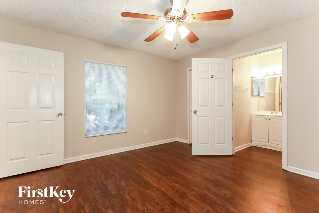 A room with a ceiling fan and wooden floors.